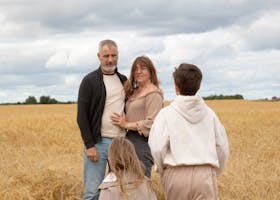 A family of four enjoying a day outdoors in a wheat field during summer.